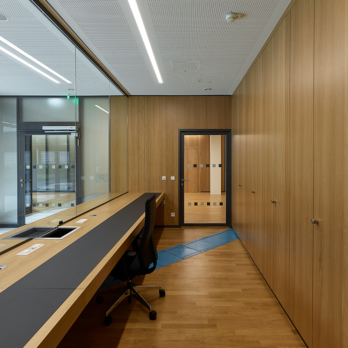 Raum im Behördenzentrum mit Schreibtisch und großer Glasfront in Richtung Foyer