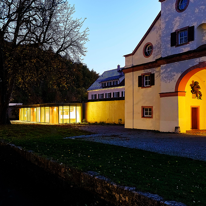 Toilettenanlage neben Schlossanlage in der Dämmerung erleuchtet