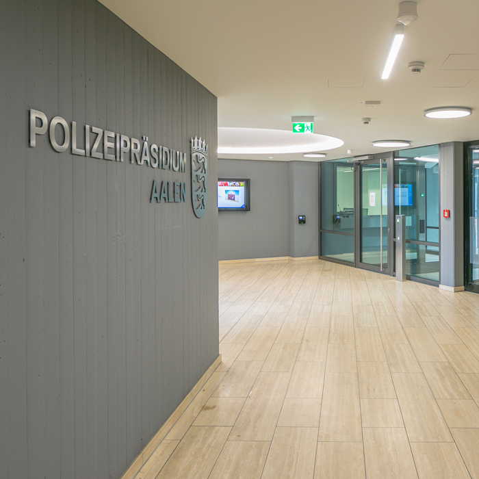 beleuchteter Eingangsbereich Polizeipräsidium Aalen mit Schriftzug und Wappen